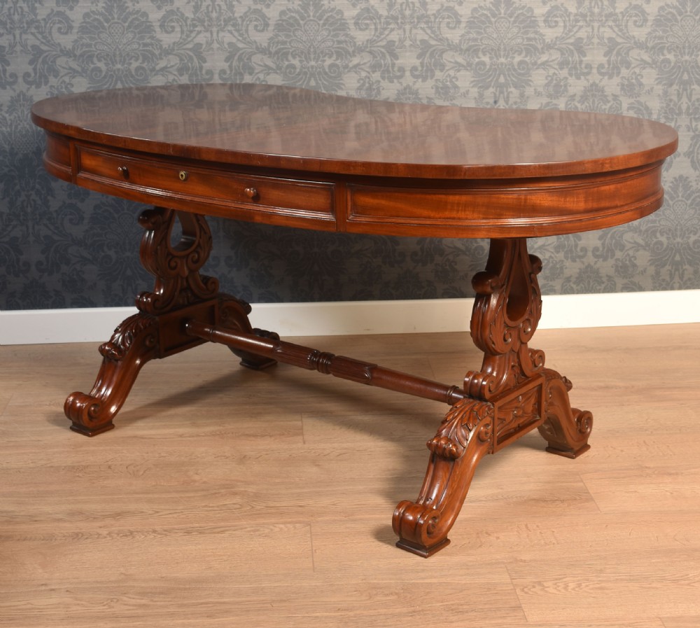A Victorian mahogany kidney-shaped desk featuring carved trestle legs, a turned stretcher, and a single frieze drawer. View XV