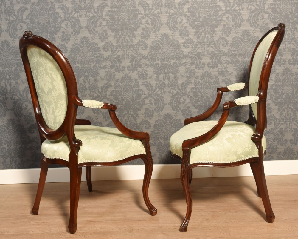 A pair of antique mahogany open armchairs featuring oval backrests, cabriole legs, and pale sage green damask upholstery. View VI