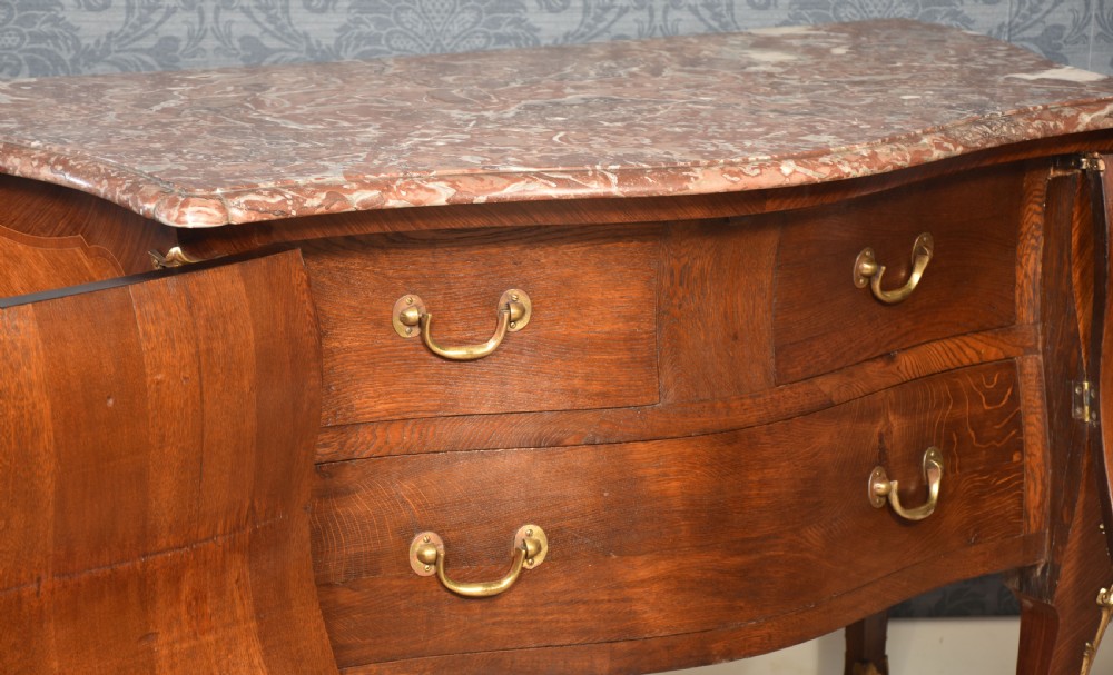 A late 18th-century French kingwood bombe commode featuring ornate gilt bronze mounts, cabriole legs, and a shaped marble top. View VII