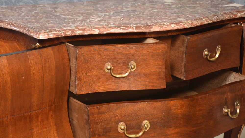 A late 18th-century French kingwood bombe commode featuring ornate gilt bronze mounts, cabriole legs, and a shaped marble top. View IX