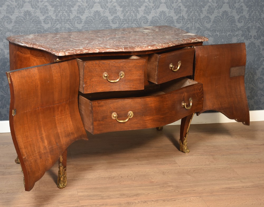 A late 18th-century French kingwood bombe commode featuring ornate gilt bronze mounts, cabriole legs, and a shaped marble top. View X