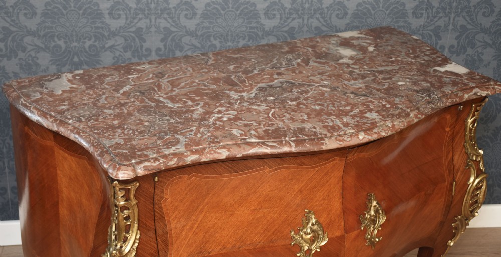 A late 18th-century French kingwood bombe commode featuring ornate gilt bronze mounts, cabriole legs, and a shaped marble top. View XI
