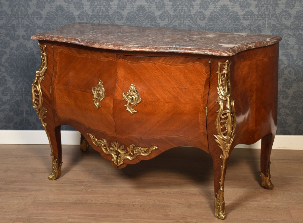 A late 18th-century French kingwood bombe commode featuring ornate gilt bronze mounts, cabriole legs, and a shaped marble top. View XIV