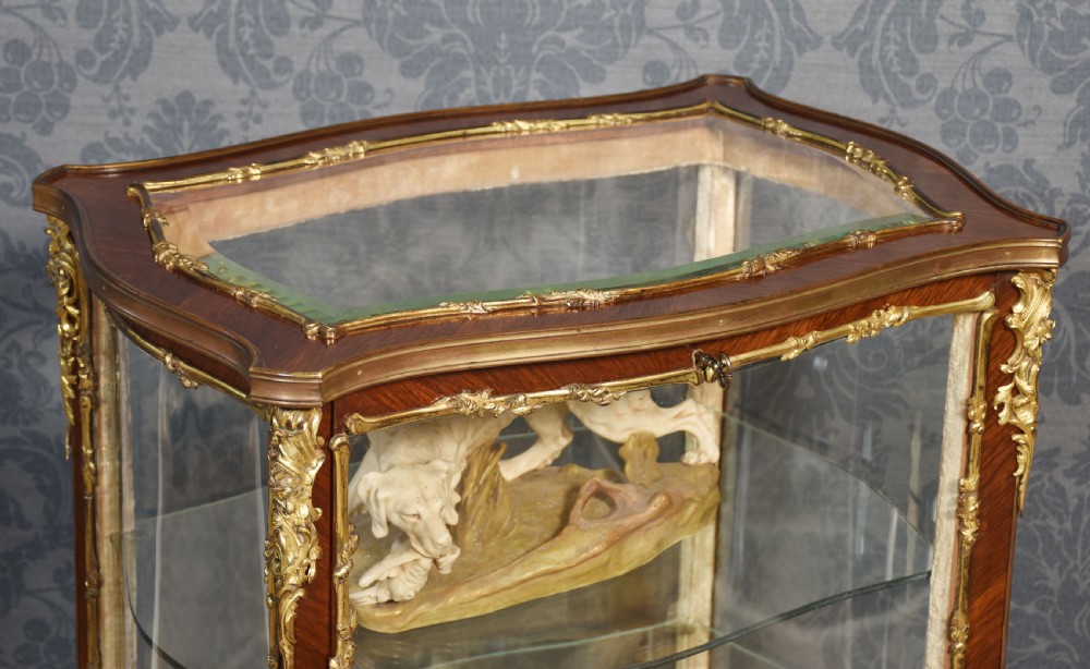 A French walnut vitrine display cabinet featuring glazed curved side panels, gilt-bronze ormolu mounts, glass shelves, and cabriole legs. View VIII