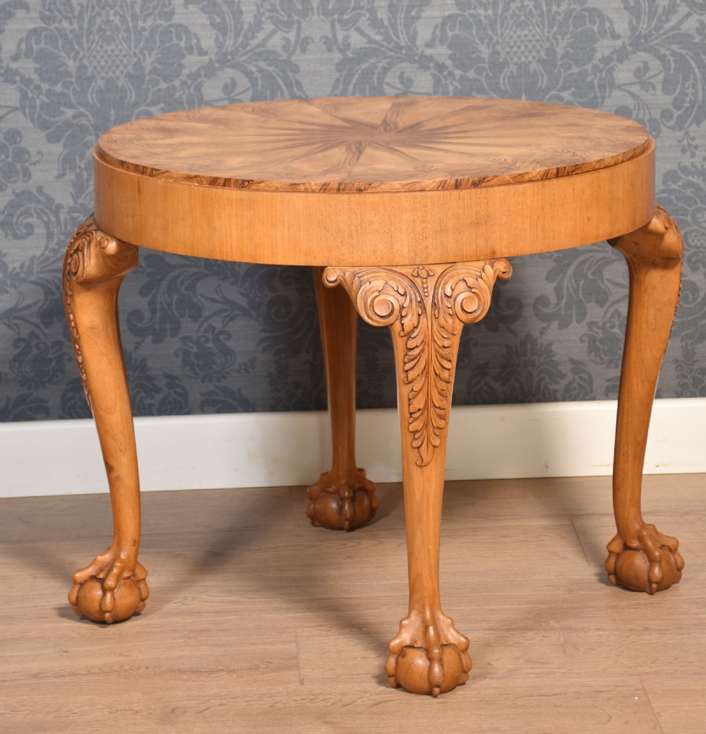 A circular low coffee table featuring a starburst burr walnut veneered top, carved cabriole legs with leaf details, and ball-and-claw feet. View II