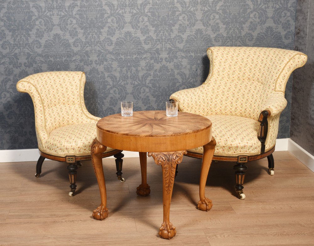 A circular low coffee table featuring a starburst burr walnut veneered top, carved cabriole legs with leaf details, and ball-and-claw feet. View V