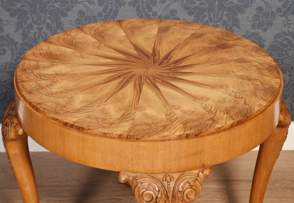 A circular low coffee table featuring a starburst burr walnut veneered top, carved cabriole legs with leaf details, and ball-and-claw feet. View VII