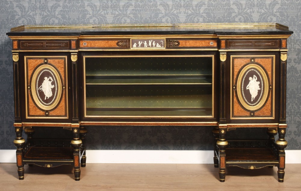 A Victorian ebonised and coromandel side cabinet featuring central glazed shelves, side doors with oval classical cameo plaques, turned legs, and gilt brass details.