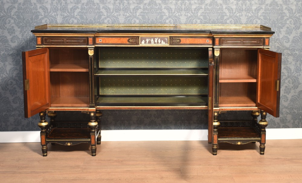 A Victorian ebonised and coromandel side cabinet featuring central glazed shelves, side doors with oval classical cameo plaques, turned legs, and gilt brass details. View VI