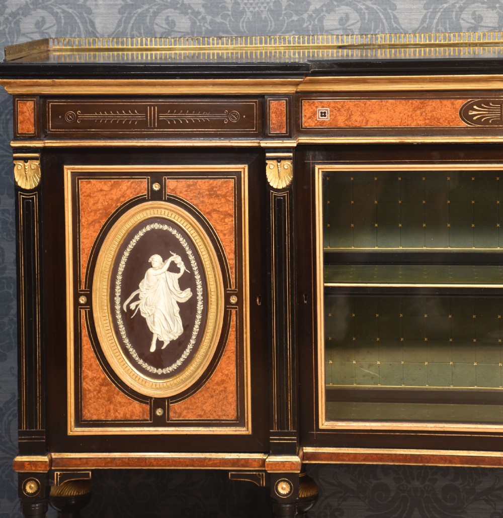 A Victorian ebonised and coromandel side cabinet featuring central glazed shelves, side doors with oval classical cameo plaques, turned legs, and gilt brass details. View VII