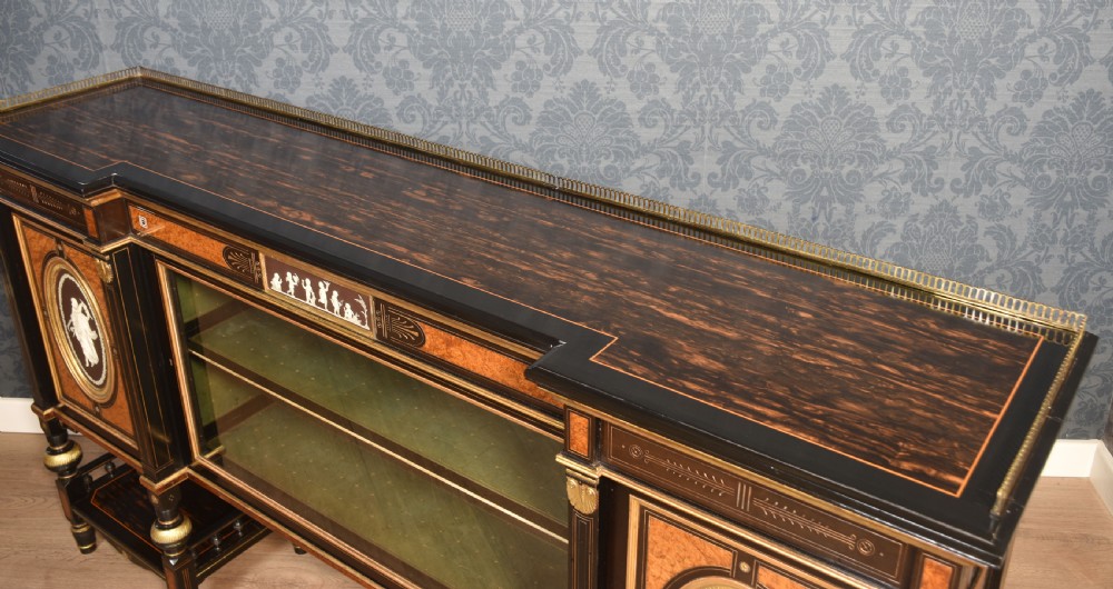 A Victorian ebonised and coromandel side cabinet featuring central glazed shelves, side doors with oval classical cameo plaques, turned legs, and gilt brass details. View XII