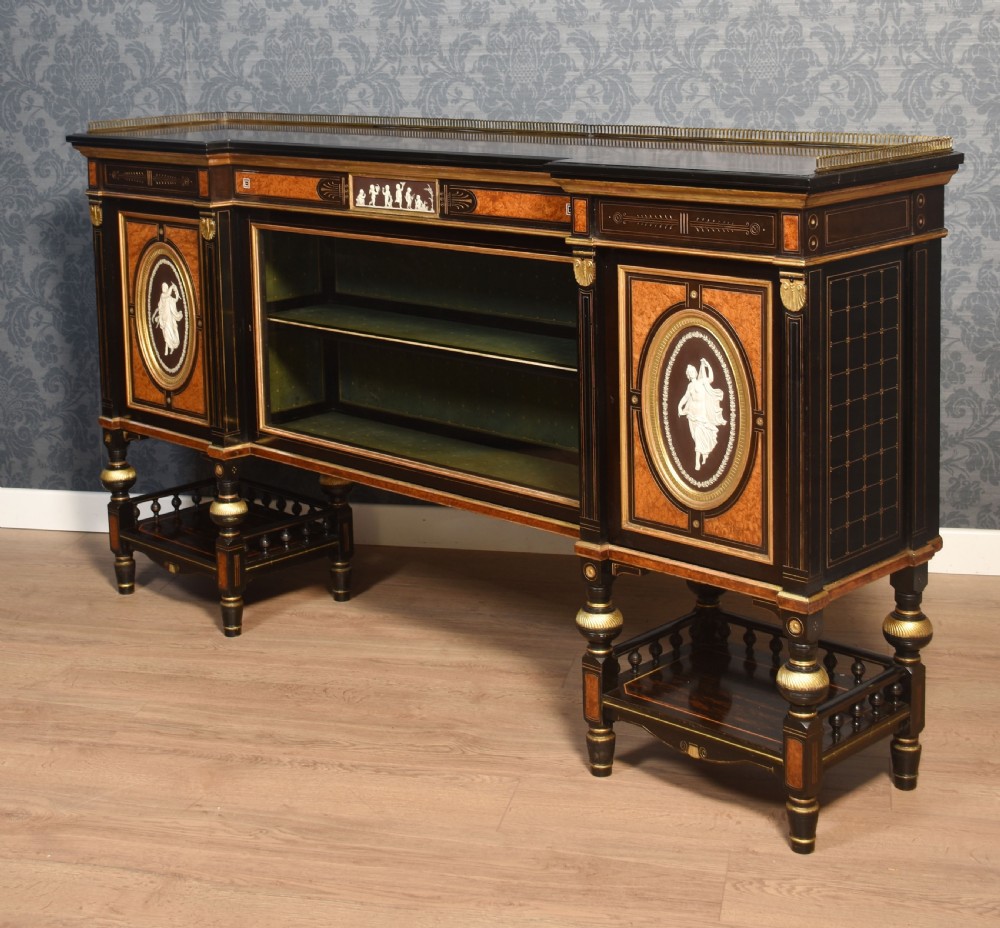 A Victorian ebonised and coromandel side cabinet featuring central glazed shelves, side doors with oval classical cameo plaques, turned legs, and gilt brass details. View XV