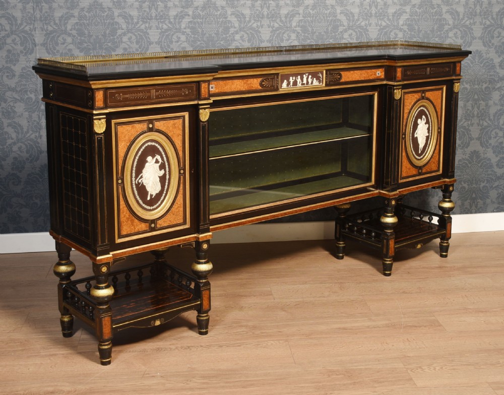 A Victorian ebonised and coromandel side cabinet featuring central glazed shelves, side doors with oval classical cameo plaques, turned legs, and gilt brass details. View XVII