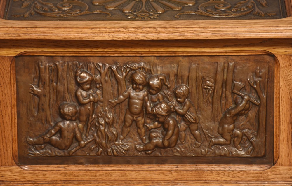 A Victorian slant-front oak slipper box featuring relief-embossed copper panels with cherubs on the front and a floral motif on the lid. View VIII