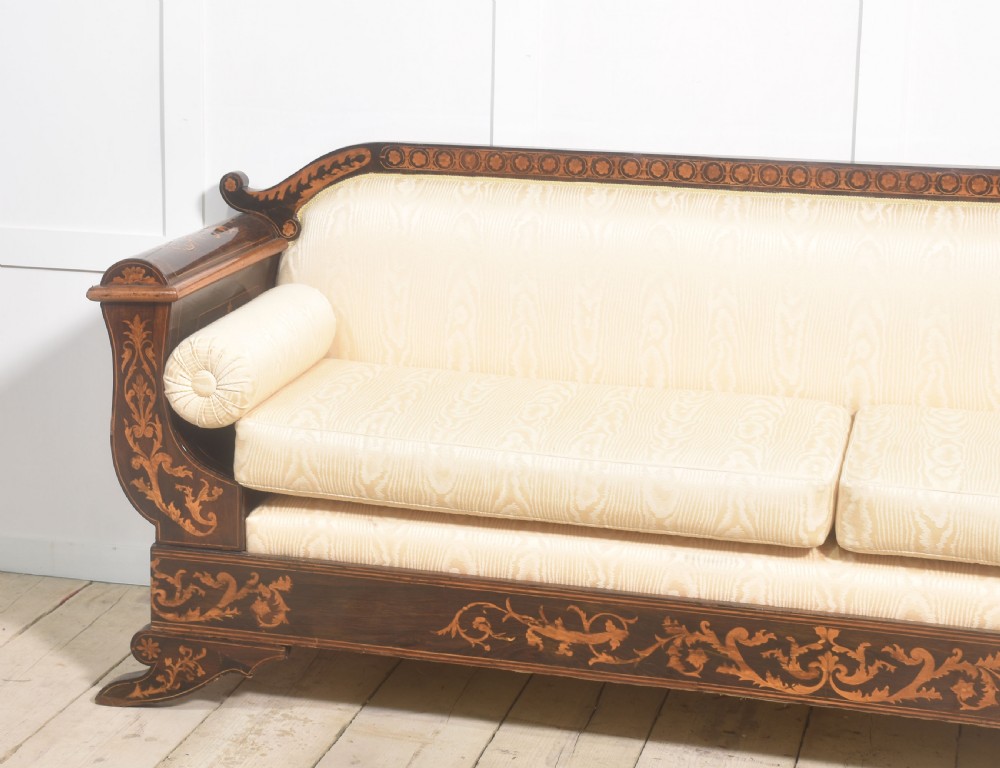 A Dutch marquetry settee with dark wood floral inlay along the frame and light cream upholstered cushions. View VI