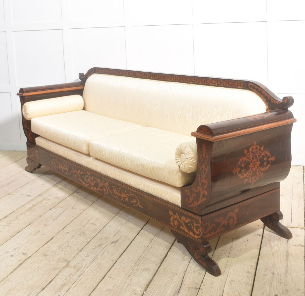 A Dutch marquetry settee with dark wood floral inlay along the frame and light cream upholstered cushions. View IX