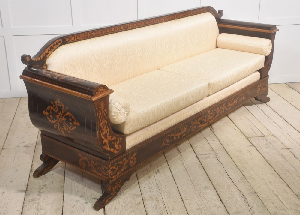 A Dutch marquetry settee with dark wood floral inlay along the frame and light cream upholstered cushions. View XIV