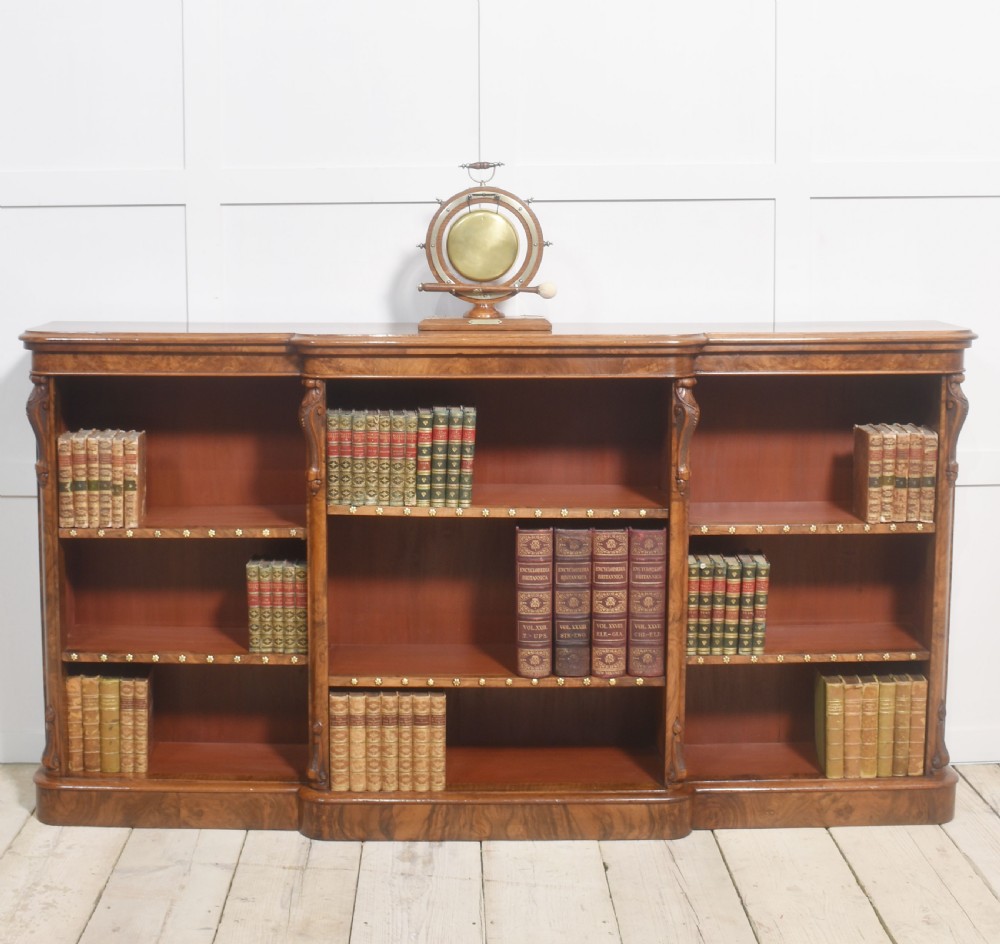An antique oak ship wheel frame holding a central suspended brass dinner gong with an accompanying wooden striker resting on brass brackets on a rectangular base. View II