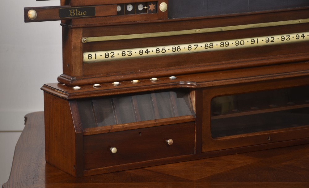 An antique Victorian mahogany billiard scoreboard featuring sliding colour pointers, a central slate panel, brass runners, and integrated ball compartments at the base. View VII