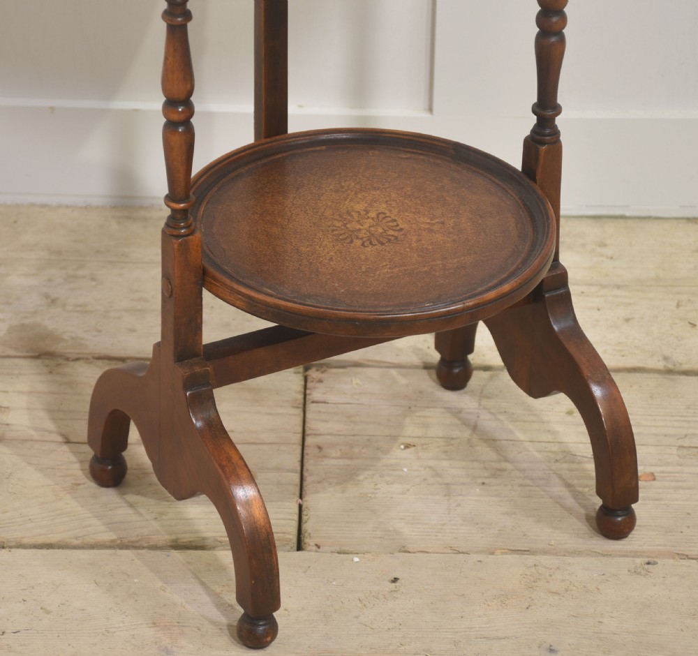A three-tier mahogany folding cake stand featuring turned wooden uprights, inlaid circular trays, and a curved top carrying handle. View III