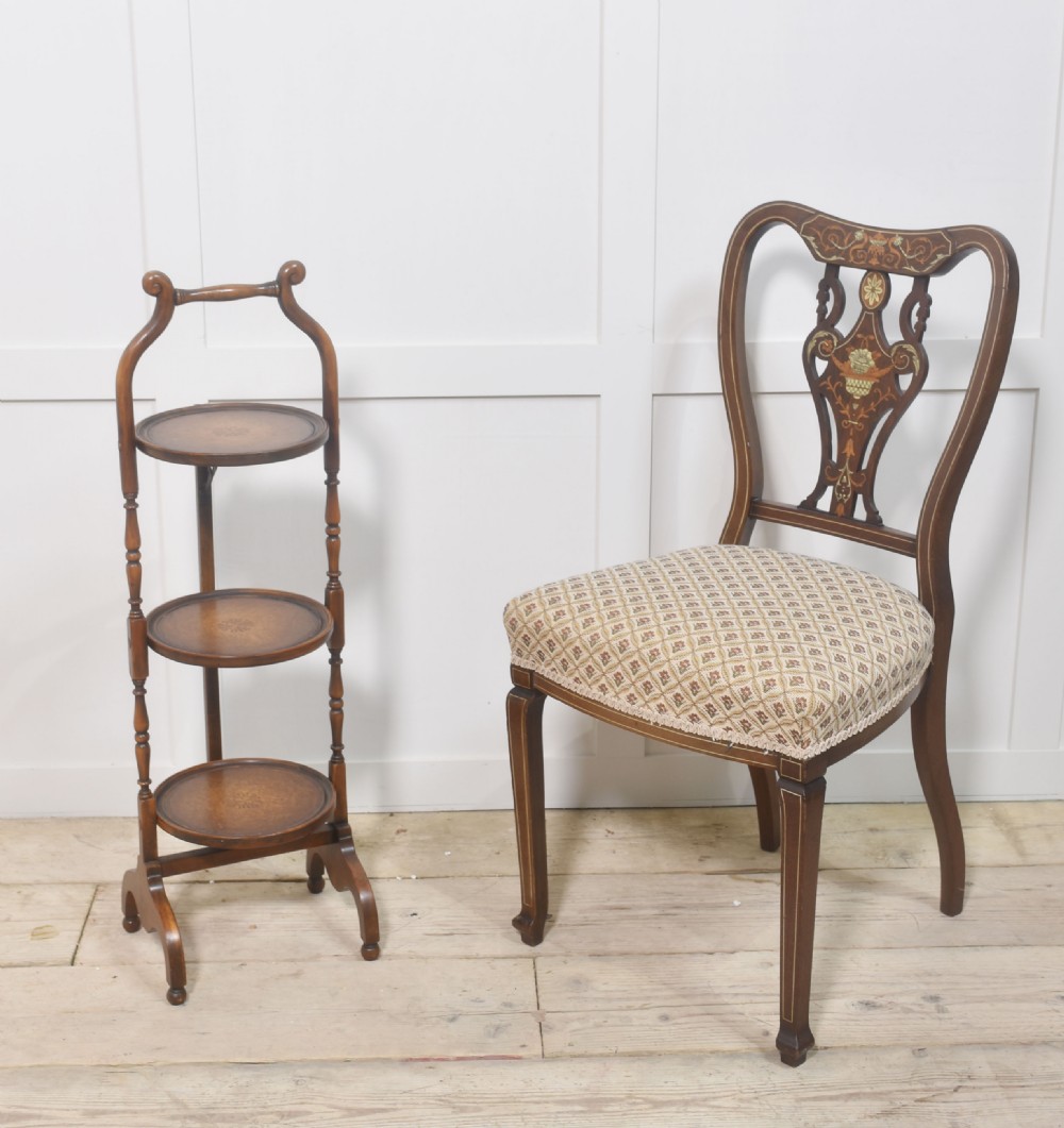 A three-tier mahogany folding cake stand featuring turned wooden uprights, inlaid circular trays, and a curved top carrying handle. View VI