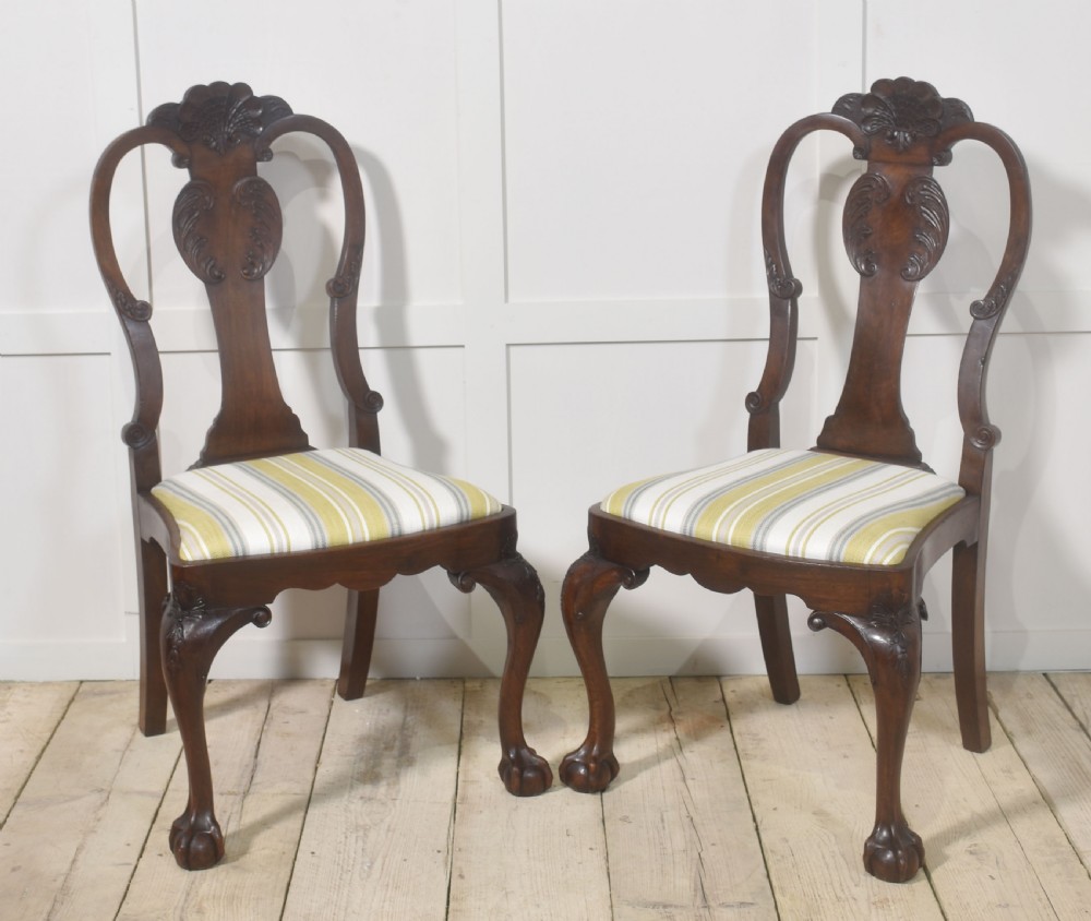 A set of eight carved dark walnut dining chairs with shell cresting rails, cabriole legs, ball-and-claw feet, and striped upholstered seat pads. View V