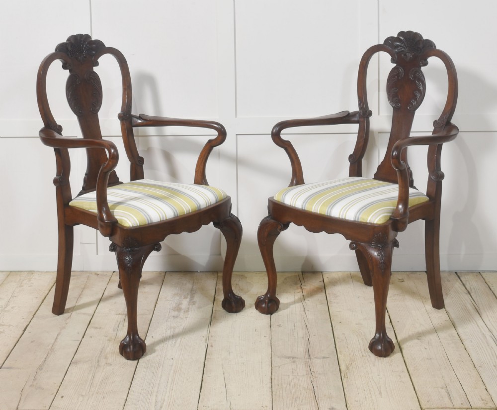 A set of eight carved dark walnut dining chairs with shell cresting rails, cabriole legs, ball-and-claw feet, and striped upholstered seat pads. View VII