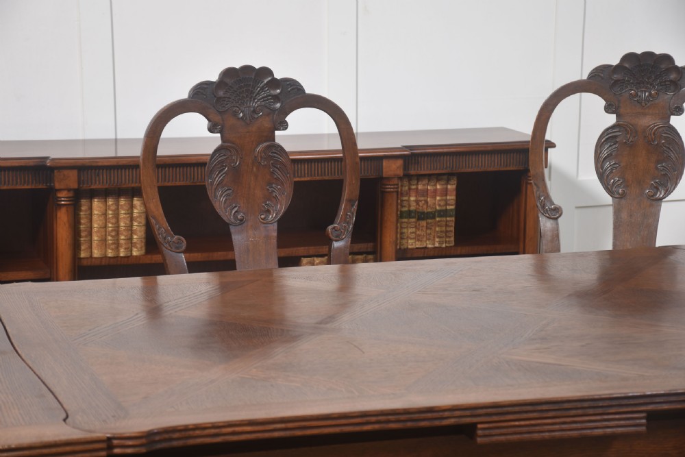 A set of eight carved dark walnut dining chairs with shell cresting rails, cabriole legs, ball-and-claw feet, and striped upholstered seat pads. View XII