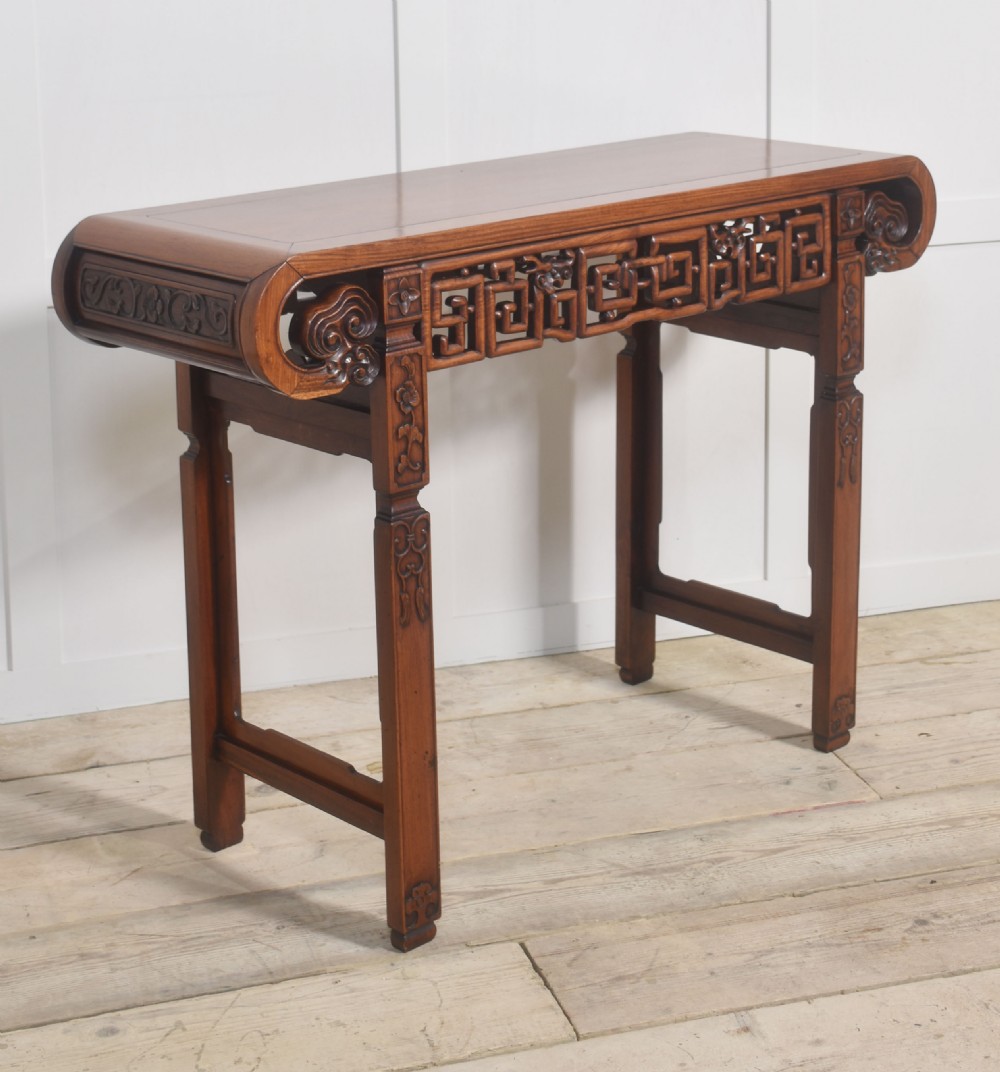A Chinese carved hardwood altar table featuring upturned everted flanges, geometric openwork fretwork along the apron, and carved square legs. View III