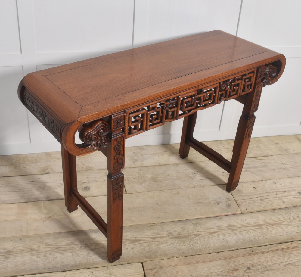 A Chinese carved hardwood altar table featuring upturned everted flanges, geometric openwork fretwork along the apron, and carved square legs. View IV