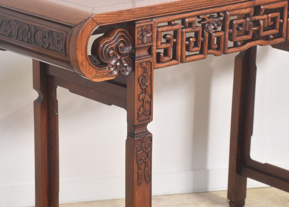 A Chinese carved hardwood altar table featuring upturned everted flanges, geometric openwork fretwork along the apron, and carved square legs. View V