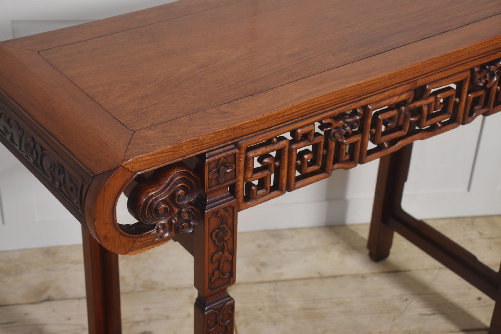 A Chinese carved hardwood altar table featuring upturned everted flanges, geometric openwork fretwork along the apron, and carved square legs. View VI