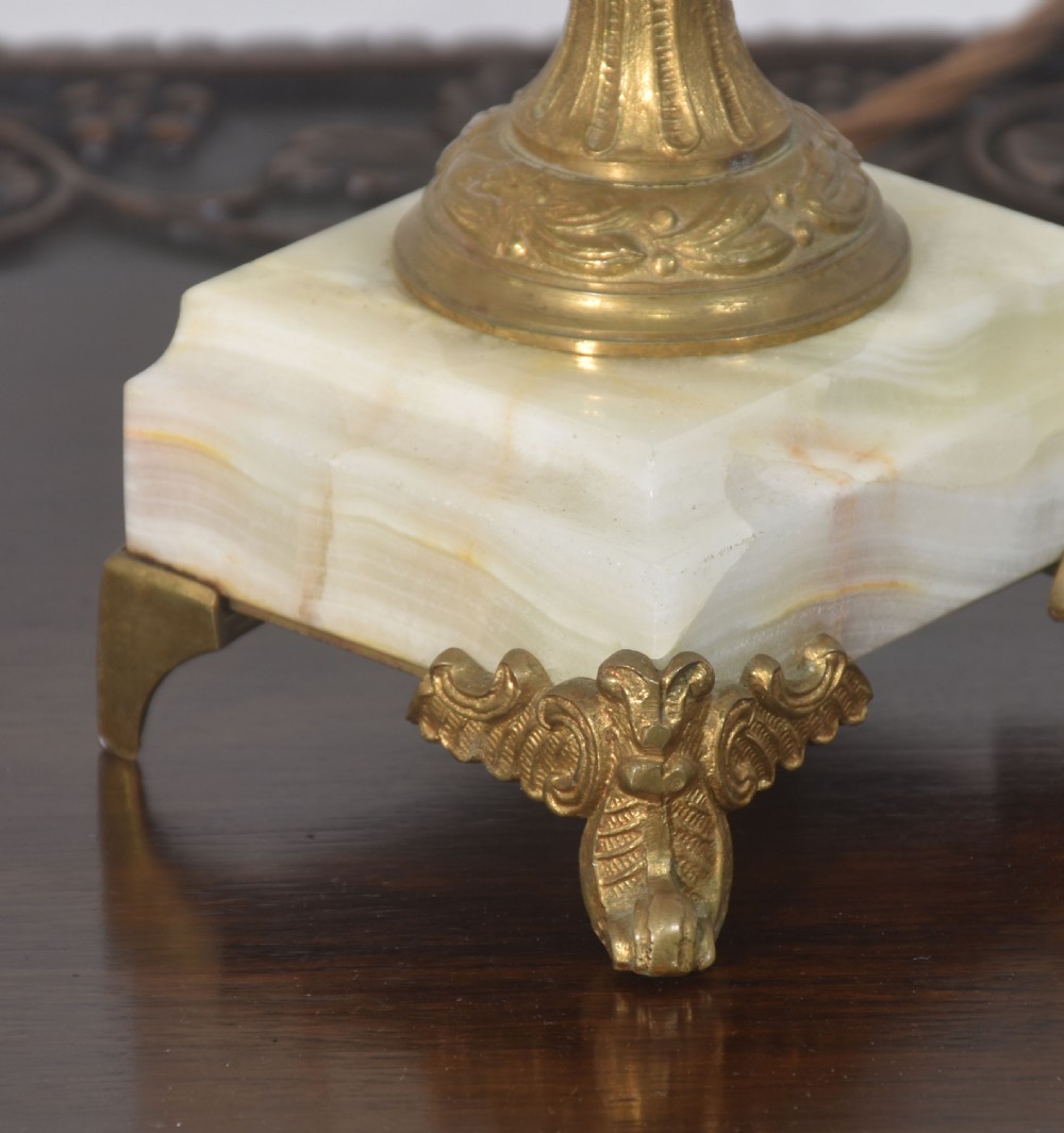 An urn-shaped onyx table lamp featuring ornate brass mounts and scrolling handles on a square onyx base with a cream fabric shade. View VI