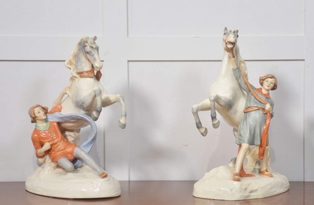 A pair of glazed cream and grey porcelain figures depicting rearing horses held by handlers on naturalistic bases. View VIII