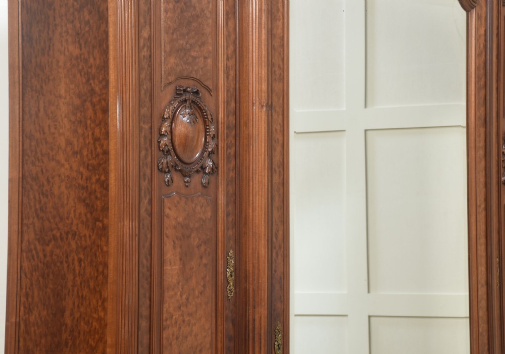 A French Louis XVI style mahogany triple armoire featuring a central mirrored door flanked by carved timber panels and lower drawers. View XIII