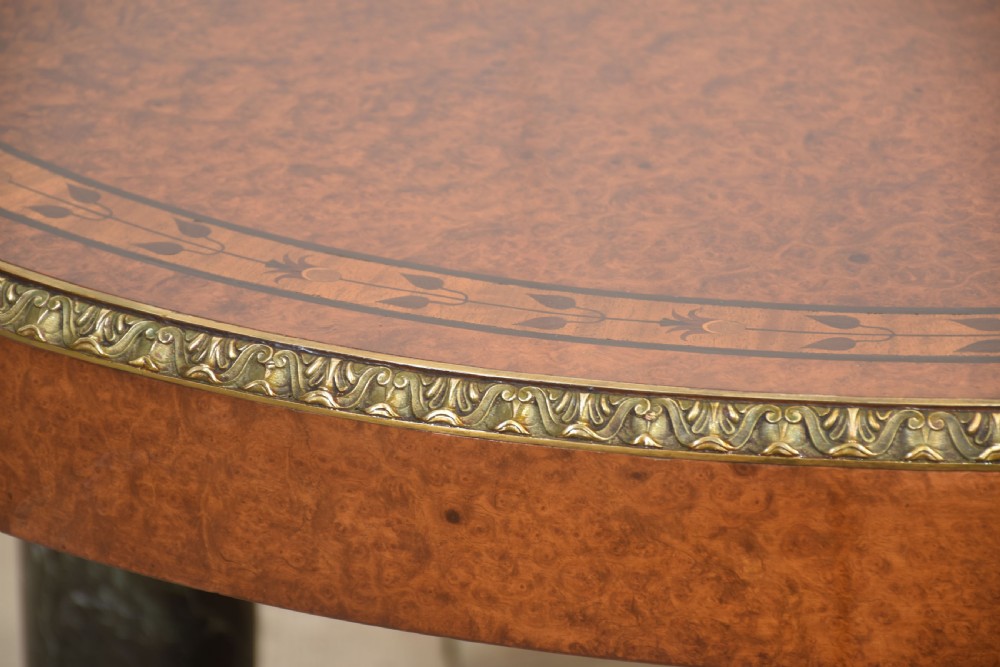 An oval centre table featuring a burr walnut marquetry top, brass rim moulding, four green marble column supports, and a curved stretcher base. View VIII