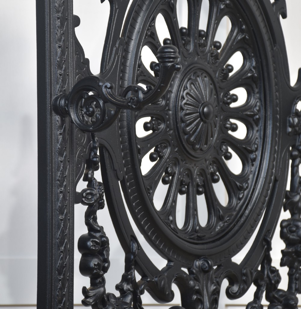 An ornate black cast iron hall stand featuring intricate scrollwork, coat hooks, an umbrella holder, and a fitted drip tray. View XII