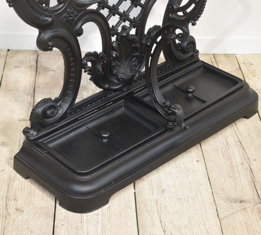 An ornate black cast iron hall stand featuring intricate scrollwork, coat hooks, an umbrella holder, and a fitted drip tray. View XIII