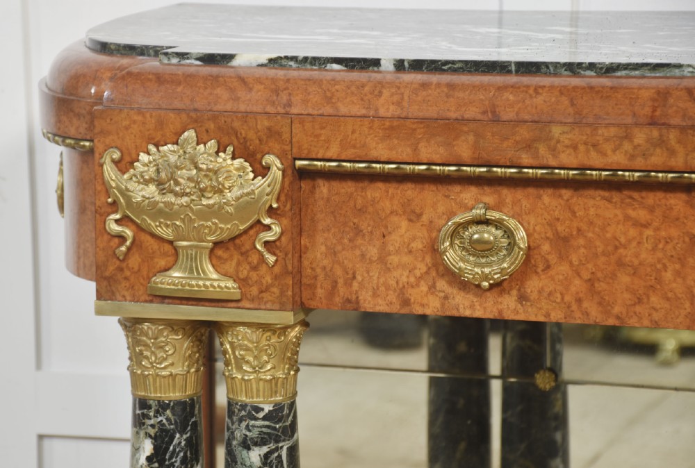 A French style console table with a dark marble top, burr timber veneer, polished marble column supports, gilt bronze mounts, and a mirrored backplate. View III