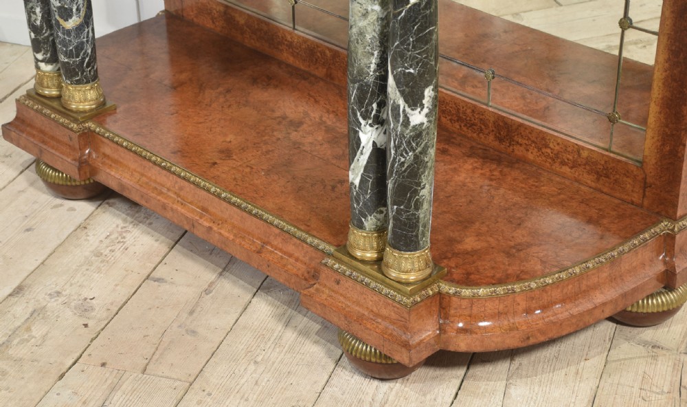 A French style console table with a dark marble top, burr timber veneer, polished marble column supports, gilt bronze mounts, and a mirrored backplate. View X