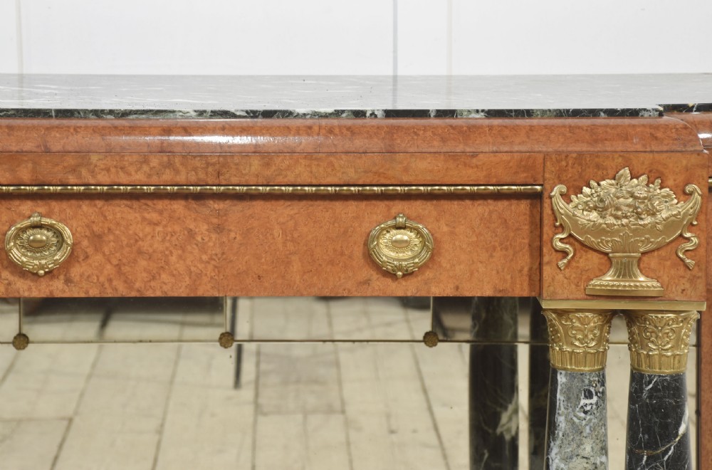 A French style console table with a dark marble top, burr timber veneer, polished marble column supports, gilt bronze mounts, and a mirrored backplate. View XIII
