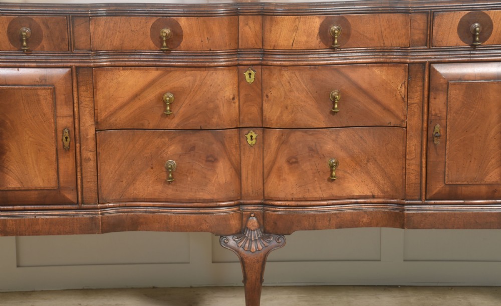 A wide walnut crossbanded Queen Anne style sideboard featuring multiple drawers, cupboard doors, drop brass handles, and carved cabriole legs. View VI