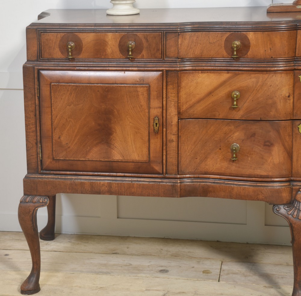 A wide walnut crossbanded Queen Anne style sideboard featuring multiple drawers, cupboard doors, drop brass handles, and carved cabriole legs. View VII