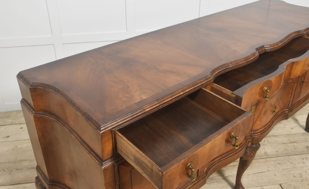 A wide walnut crossbanded Queen Anne style sideboard featuring multiple drawers, cupboard doors, drop brass handles, and carved cabriole legs. View XII