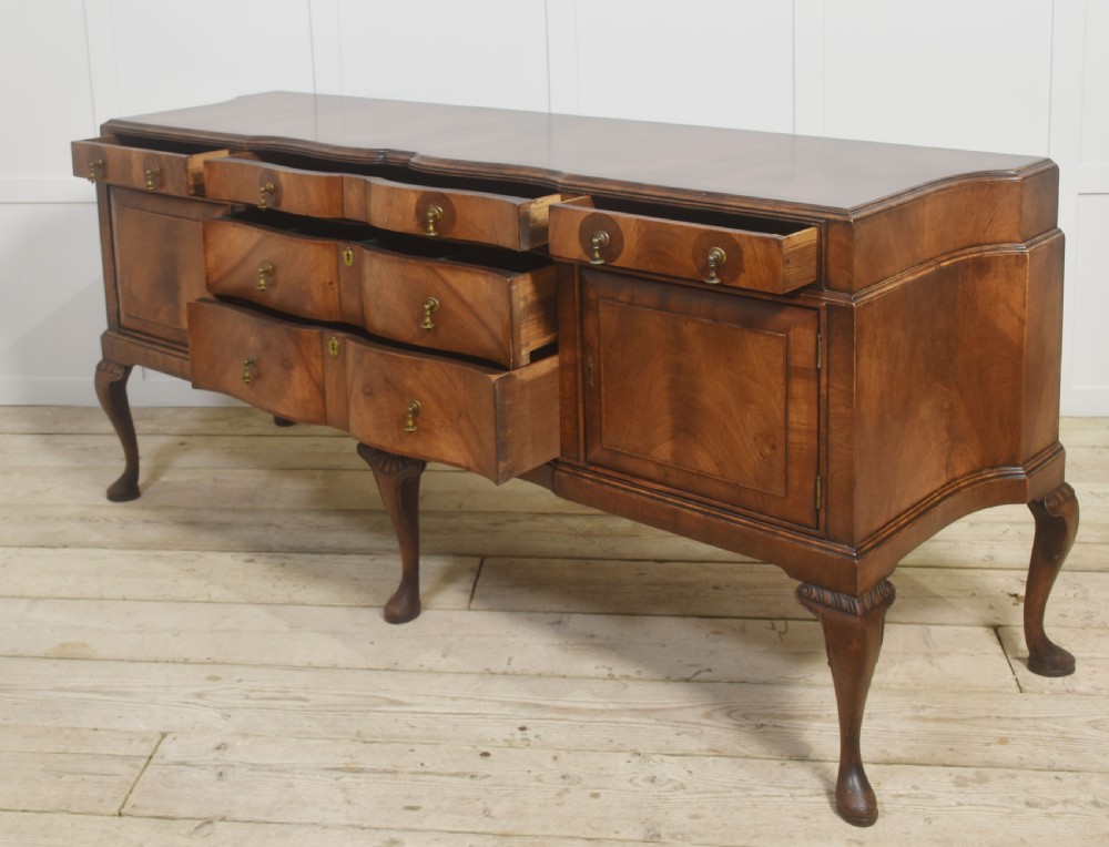A wide walnut crossbanded Queen Anne style sideboard featuring multiple drawers, cupboard doors, drop brass handles, and carved cabriole legs. View XV