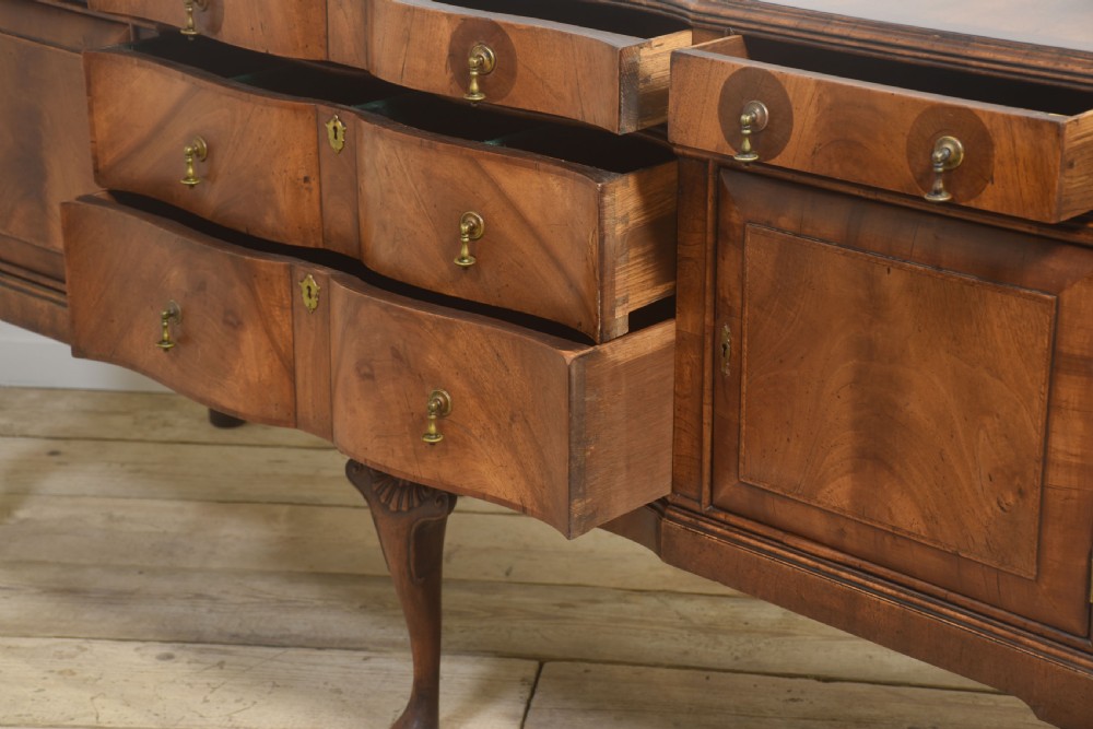 A wide walnut crossbanded Queen Anne style sideboard featuring multiple drawers, cupboard doors, drop brass handles, and carved cabriole legs. View XVI