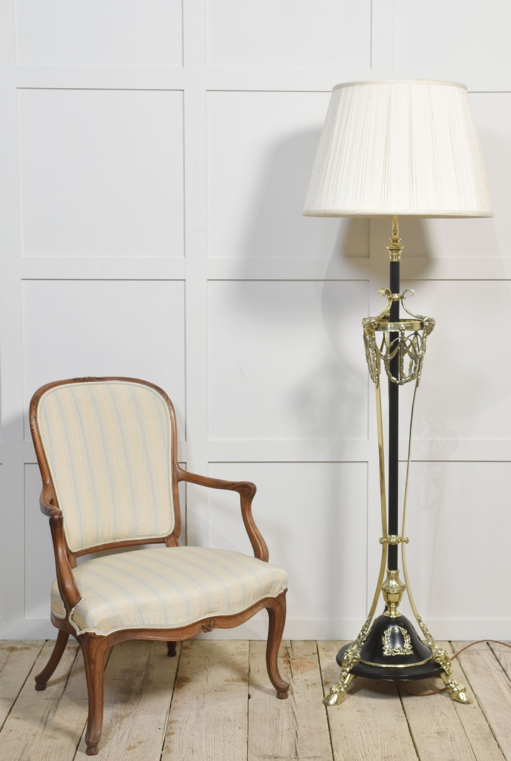 A Neoclassical brass and black standard lamp with an ornate tripod base, classical garland decorations, and a cream pleated fabric shade. View IX