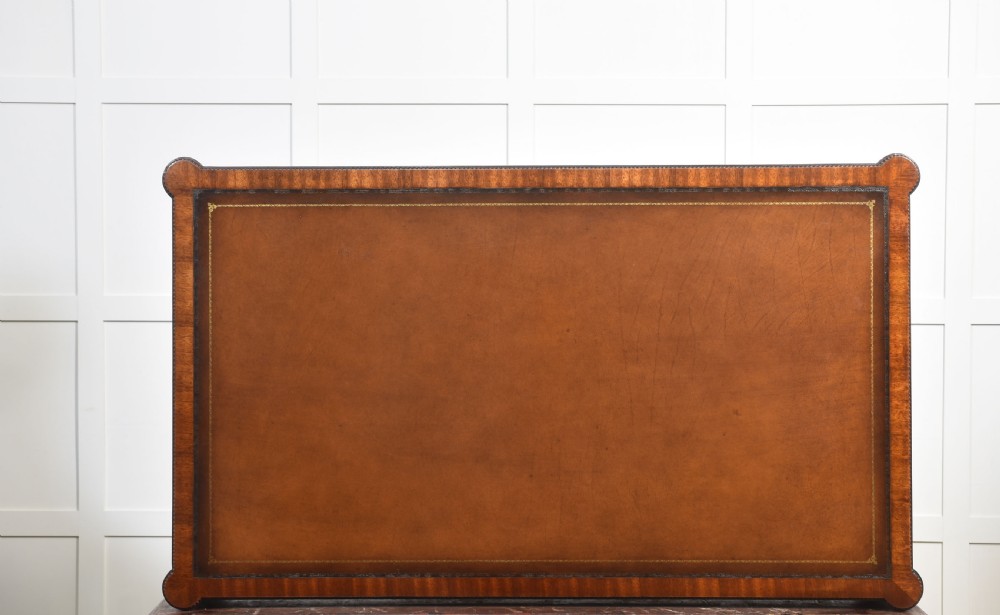 An antique mahogany writing table featuring three frieze drawers with brass handles, a leather inset top, and slim reeded legs with brass castors. View XIV