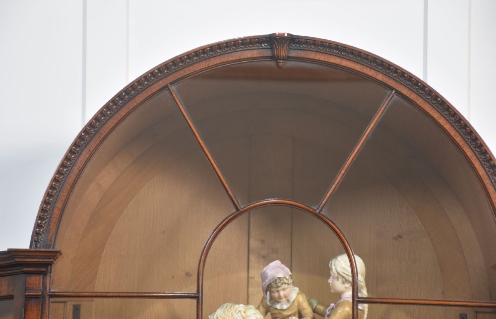 A large mahogany glazed display cabinet featuring an arched central section with glass doors, flame mahogany drawer fronts, and oval inlaid cupboard panels. View III