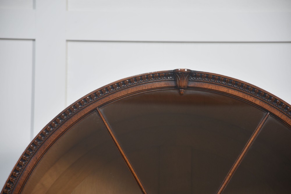 A large mahogany glazed display cabinet featuring an arched central section with glass doors, flame mahogany drawer fronts, and oval inlaid cupboard panels. View V